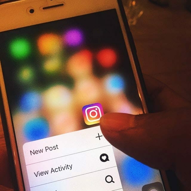 woman scrolling through her iPhone and clicking on the instagram app